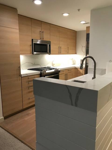 A kitchen with wood cabinets and white counters.